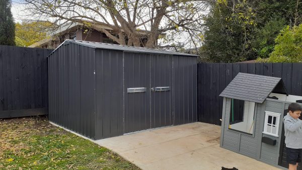 Garden Shed at end of pathway against two fences.